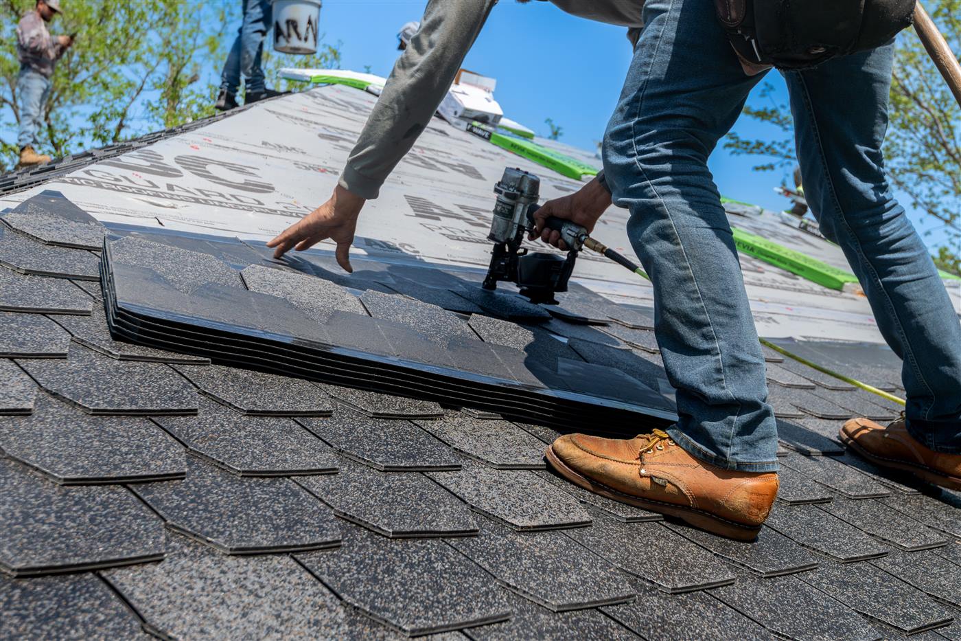 Roofer repairing shingles to stop a roof leak at its source