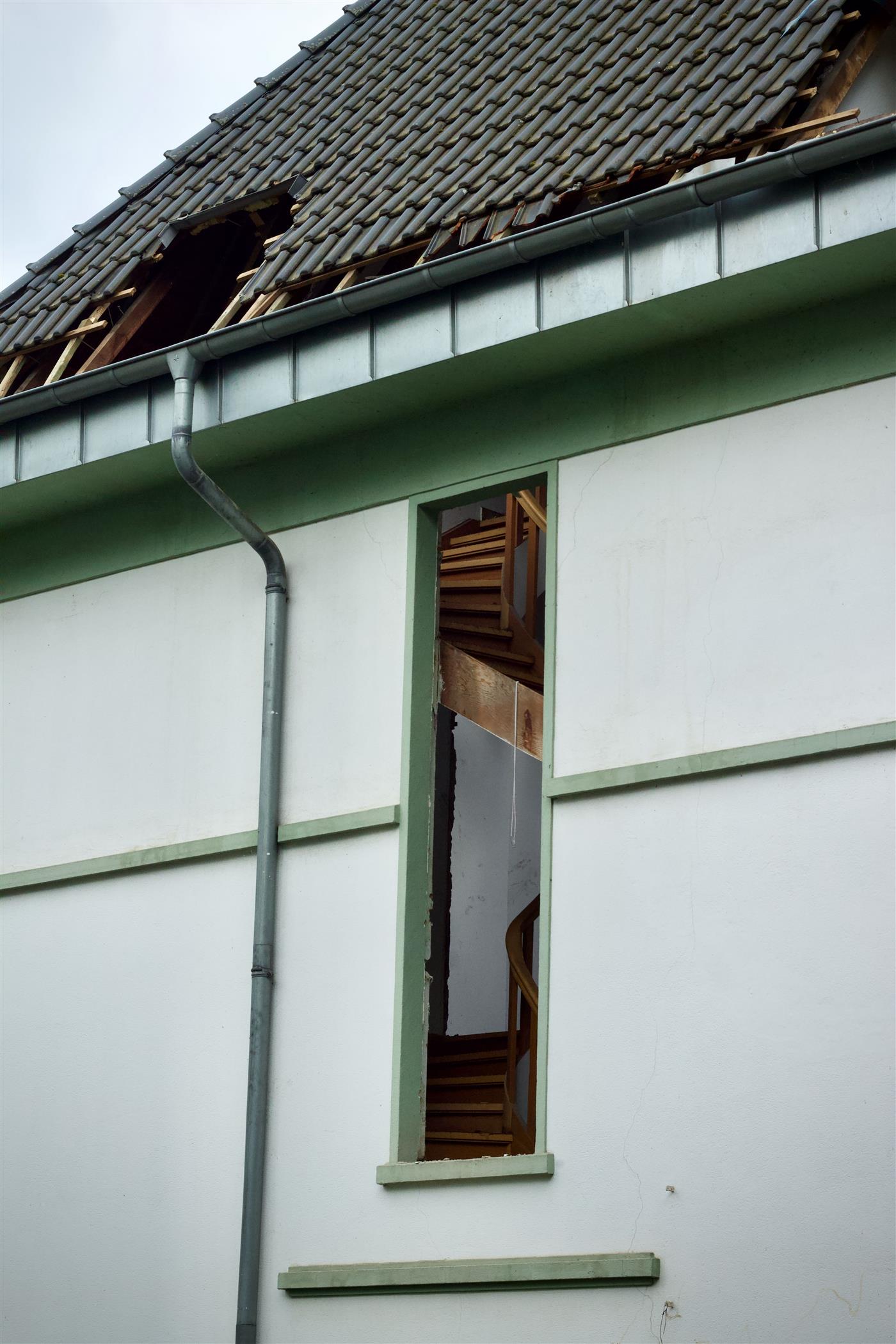 Storm damaged roofline and downspout showing the kind of damage that leads to gutter repair