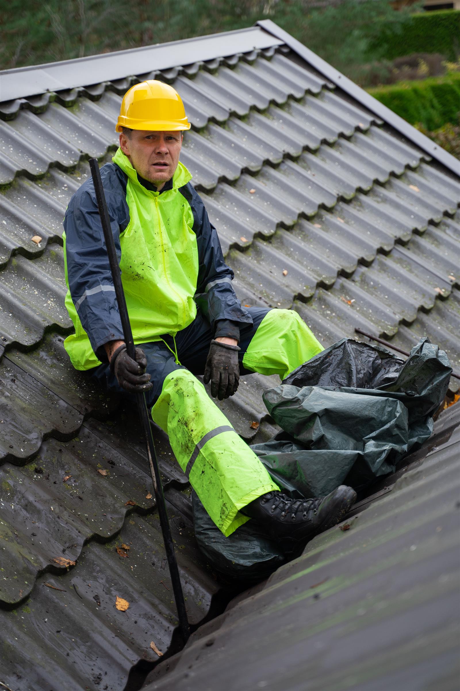 Roofer checking a roof valley and flashing for the source of a leak