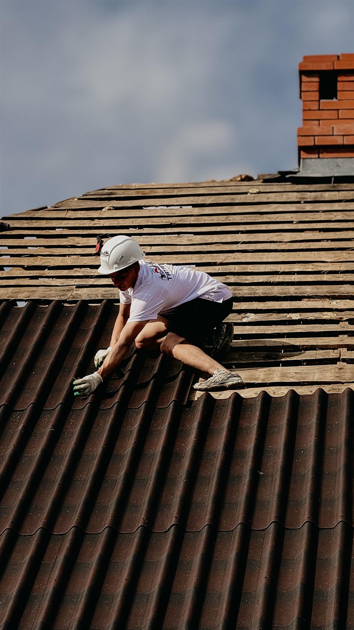 Roofer tearing off an aging roof down to the deck in Jacksonville